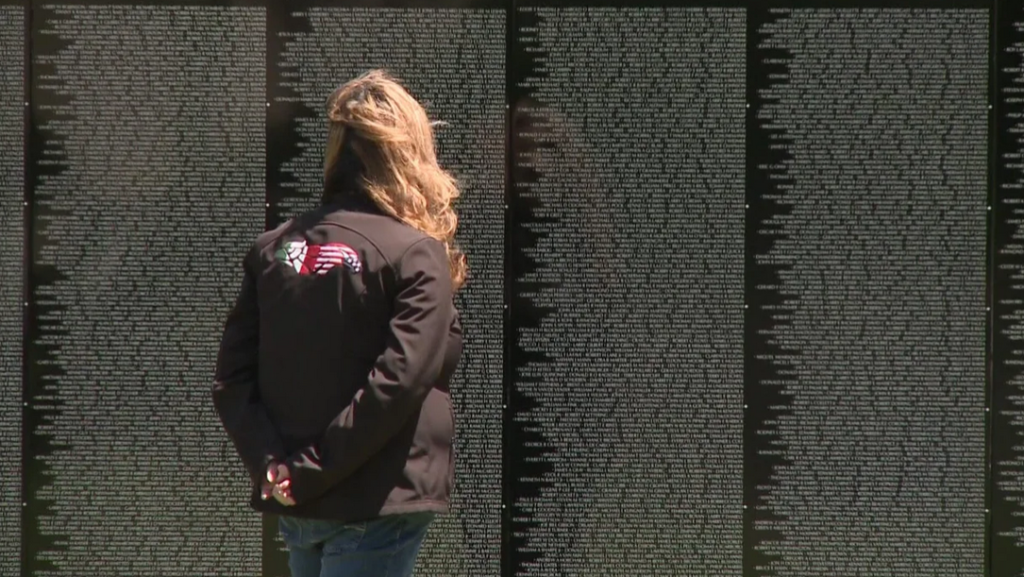Gina Pittman, the daughter of Medal of Honor recipient Richard Pittman, reflected in front of the names of her father's dear comrades, who died when his platoon was ambushed in 1966.