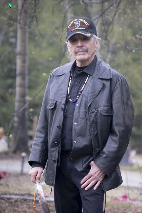 Vietnam veteran Benno Cleveland is Iñupiaq, one of the Indigenous peoples of the Arctic. He holds an eagle feather as he stands in the cemetery where he plans to be buried.