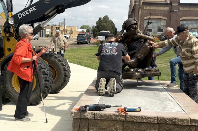 Sculptor Pamela Harr, left, watches as a crew carefully lowers her bronze sculpture, "Letters from Home," into position during its installation at Veterans Memorial Park Saturday.
Jamie Crisafulli/Glendive Ranger Review